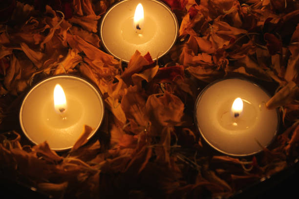 Close-up of burning Tea light candles and fresh marigold flower petals