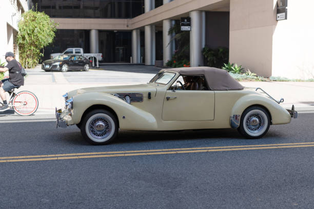 Vintage, luxury, convertible car parked on riverbank, 25 of April Bridge in distance, Lisbon