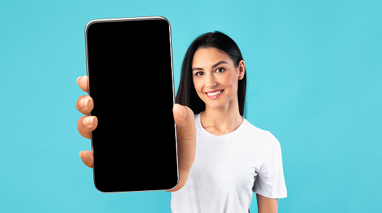Maqueta de aplicación móvil. Hermosa joven que muestra un gran teléfono inteligente con pantalla negra photo