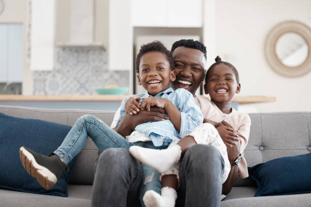 Cropped portrait of an affectionate young family of three relaxing in the living room at home Bonding with dad young family stock pictures, royalty-free photos & images