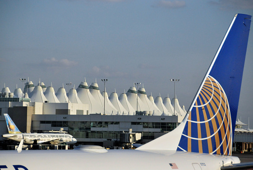 Denver, Colorado, USA: United Airlines (Star Alliance) Boeing 737 aircraft and Frontier Airlines Airbus  A318 at Denver International Airport, an hub for both airlines - main terminal with its famous tensile structure in the background (Jeppesen Terminal).