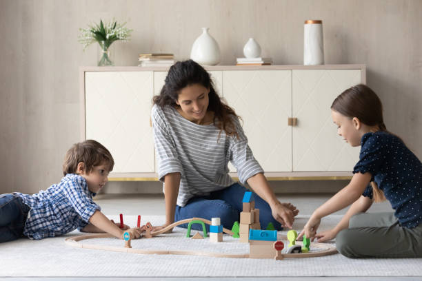 istock Happy young mum playing toys with small kids. 1352867520