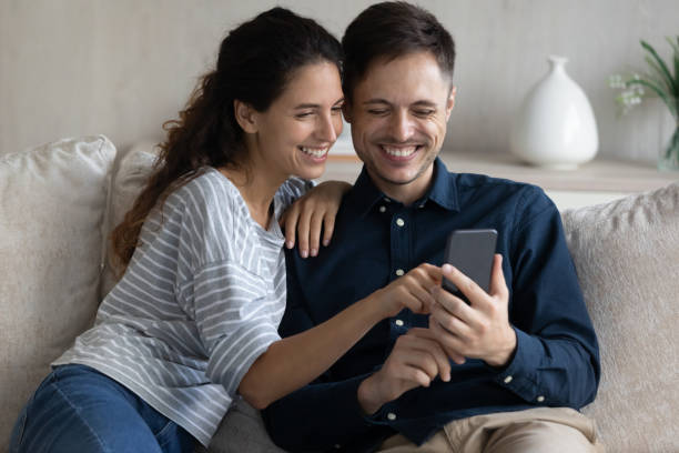 istock Laughing beautiful millennial latin couple using smartphone. 1352867655