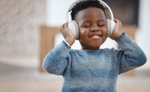 自宅で一日の間にヘッドフォンを通して音楽を聴く愛らしい小さな男の子のショット - one little boy audio ストックフォトと画像
