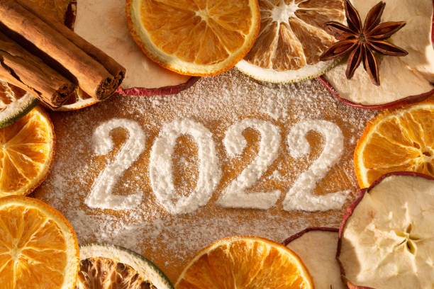 jahreswechsel 2021/22 - jahresdatum aus puderzucker mit getrockneten apfel-, limetten- und orangenscheiben - turn back stock-fotos und bilder
