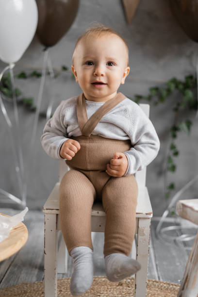 porträt eines kleinen jungen an seinem ersten geburtstag, süßes baby auf einem stuhl posiert, hintergrunddekoration. - beautiful one person men male stock-fotos und bilder