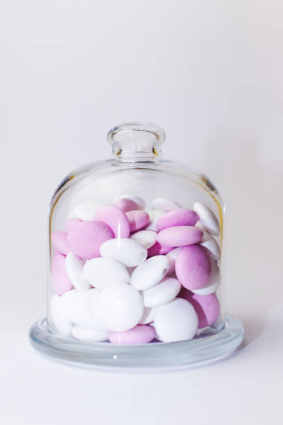 istock Pink and white peppermint candies in a glass jar on a white background - vertical 1352873429