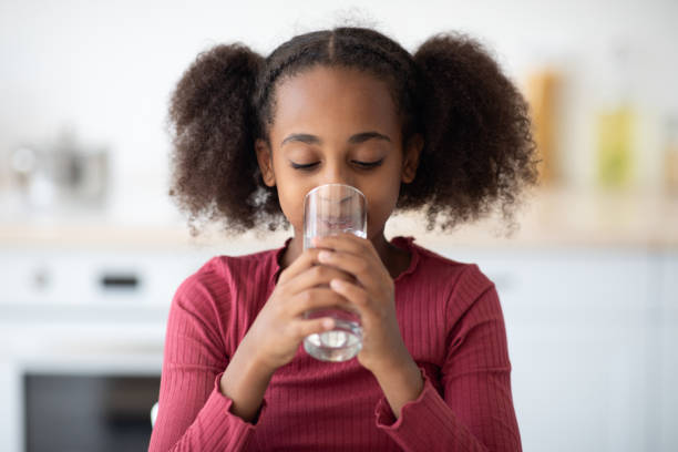istock Pretty black girl drinking water, kitchen interior 1352873585