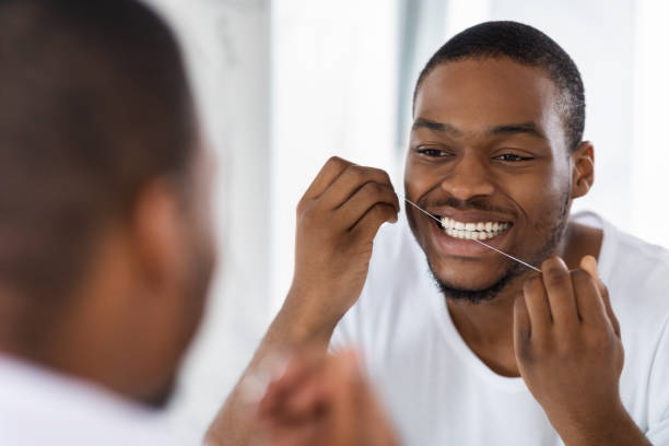 istock Oral Hygiene. Young African American Guy Using Dental Floss In Bathroom 1352874229