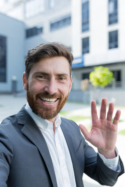 istock vertical view smartphone camera Caucasian bearded businessman speaks on phone using a front camera on a video call. employee business man talking on webcam. Conversation of an office worker in suit 1352875374