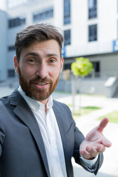 istock vertical view smartphone camera Caucasian bearded businessman speaks on phone using a front camera on a video call. employee business man talking on webcam. Conversation of an office worker in suit 1352875776