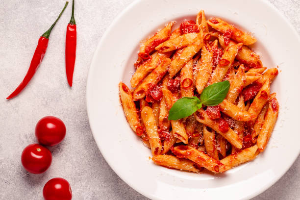 istock Classic italian pasta penne alla arrabiata with fresh basil on a light background, top view 1352878799