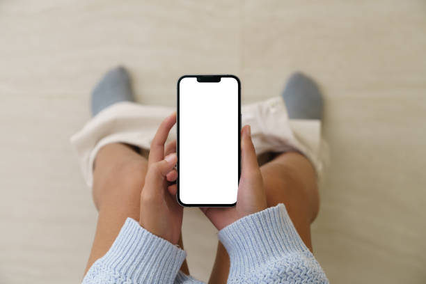 Woman holding a phone while using the toilet, Mock up phone  white screen display in hand stock photo