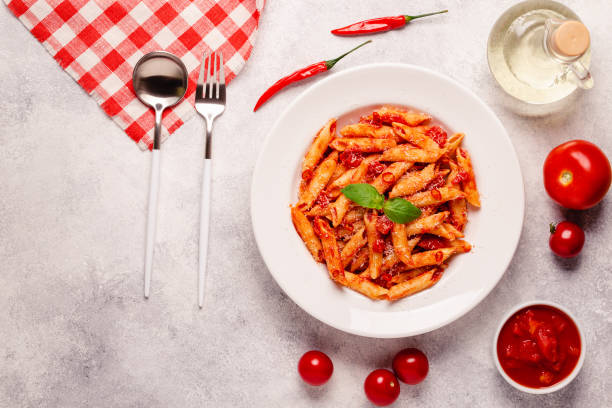 istock Classic italian pasta penne alla arrabiata with fresh basil on a light background, top view 1352878858