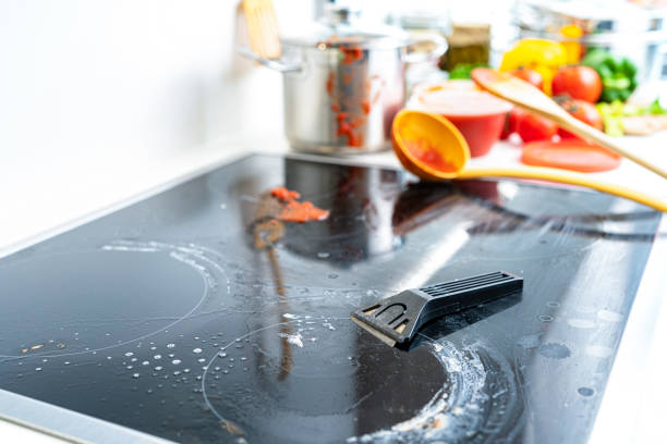 Close up view of a ceramic hob scraper placed on dirty glass stove top. High resolution 42Mp indoors digital capture taken with SONY A7rII and Zeiss Batis 40mm F2.0 CF lens