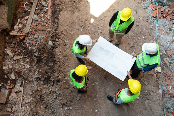 istock Construction workers and architect reviewing blueprint at building site 1352878983