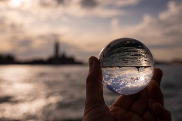 istock Hand holding glass sphere in front of sunset 1352880329