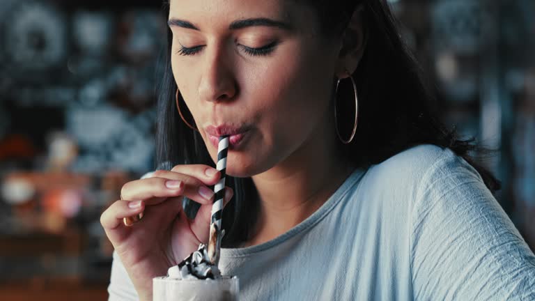 4k video footage of a young woman enjoying a milkshake in a restaurant