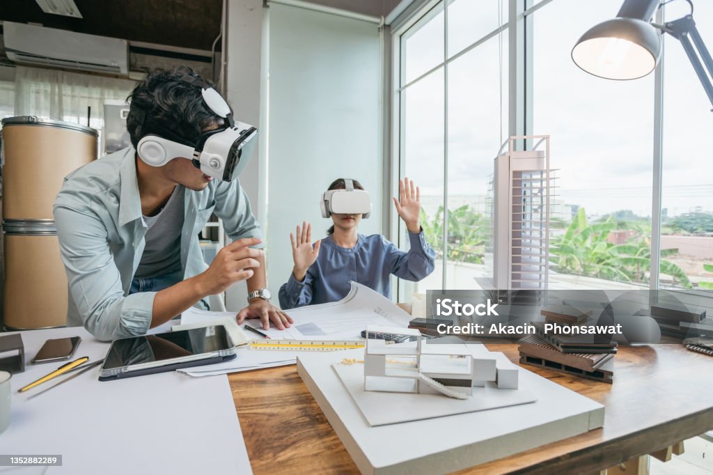 Arquitecto de equipo o diseñador de ingeniería con auriculares VR para tecnología BIM que trabajan juntos diseñando modelos 3D en la oficina. - Foto de stock de Simulador de realidad virtual libre de derechos