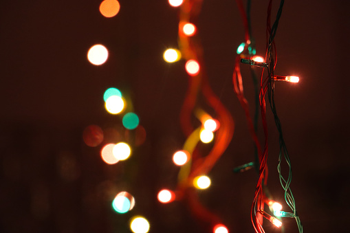 Stock photo showing a defocused image of white and green fairy lights sparkling against a black background.