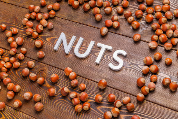 istock the word nuts laid with silver letters on wooden board background surrounded with scattered hazelnuts 1352887328