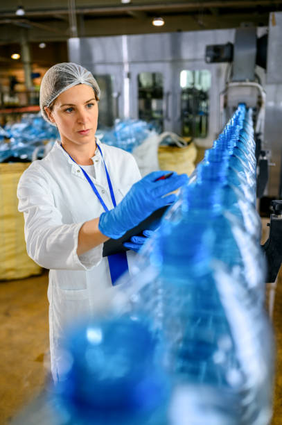 istock Technologist in bottling factory checking water bottles before shipment. 1352887589