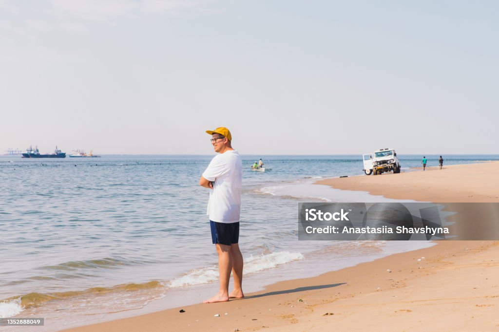 Man traveler walking at the remote beach exploring the beautiful landscape at Sandwich Harbour, Namibia Young man traveling in Namibia, walking at the and beach looking at ocean at the ships and ocean at Namib-Naukluft National Park Achievement Stock Photo
