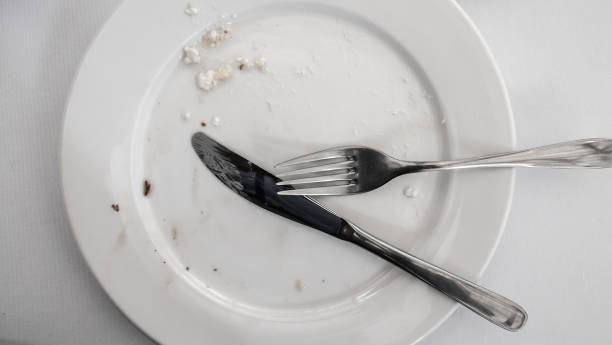 Empty plate with a knife and fork Top view of an empty used plate with a knife and fork placed on it insufficient funds stock pictures, royalty-free photos & images