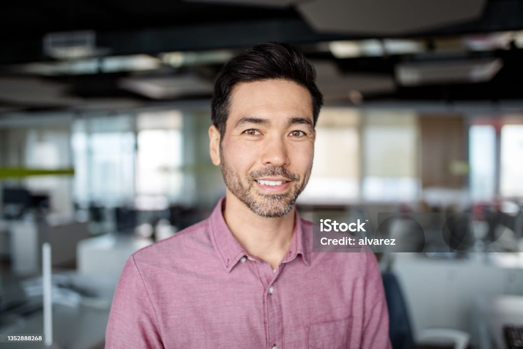 Close-up portrait of Japanese mature businessman in the office Close-up portrait of Asian mature businessman in the office. Japanese business executive with light beard smiling at the camera. Headshot Stock Photo