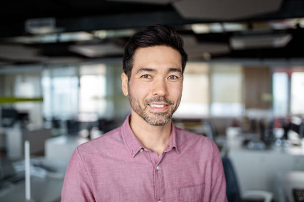 Close-up portrait of Japanese mature businessman in the office Close-up portrait of Asian mature businessman in the office. Japanese business executive with light beard smiling at the camera. headshot stock pictures, royalty-free photos & images