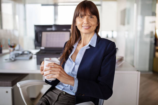 retrato de una mujer de negocios tomando un café en la oficina - director creativo fotografías e imágenes de stock