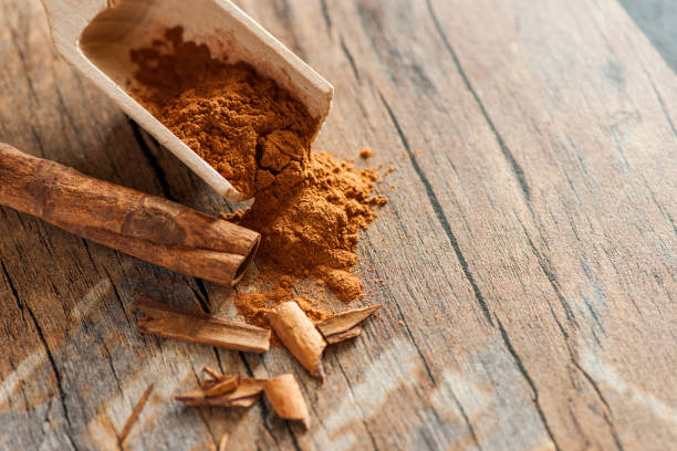 Broken cinnamon in elevated view F 5.6 Close-up, elevated view of a wooden scoop with cinnamon powder and cinnamon fragments on an old wooden surface in an elevated view at aperture F / 5.6 gebrochen stock pictures, royalty-free photos & images