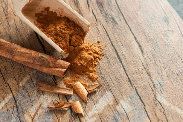 Broken cinnamon in elevated view F 11 Close-up elevated view on wooden scoop with cinnamon powder and cinnamon fragments on old wooden background in elevated view at aperture F/11. gebrochen stock pictures, royalty-free photos & images