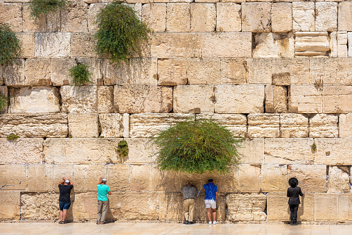 The Wailing Wall, Jerusalem, Israel - November 11, 2021: Jewish orthodox believers reading the Torah and praying facing the Western Wall, also known as Wailing Wall in the old city in Jerusalem, Israel.