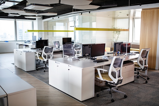 Interior of open plan office space with no people. Brightly lit office interior with computer terminal desks.