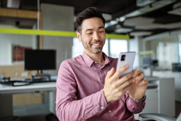 Japanese man sitting at his desk using mobile phone