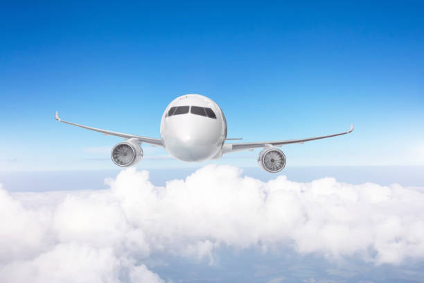 istock Airplane flies over cumulus clouds, exactly front view. 1352891286