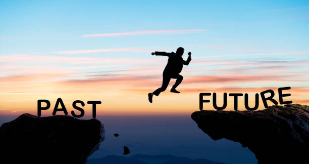 istock Businessman jumping cliff from past to future 1352892533
