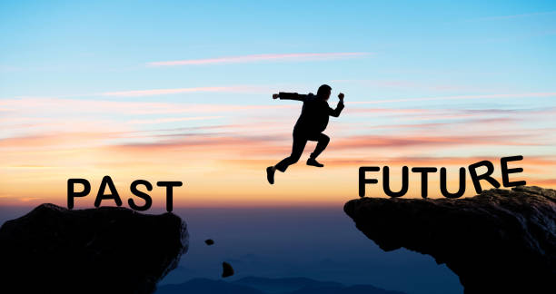 Businessman jumping cliff from past to future stock photo