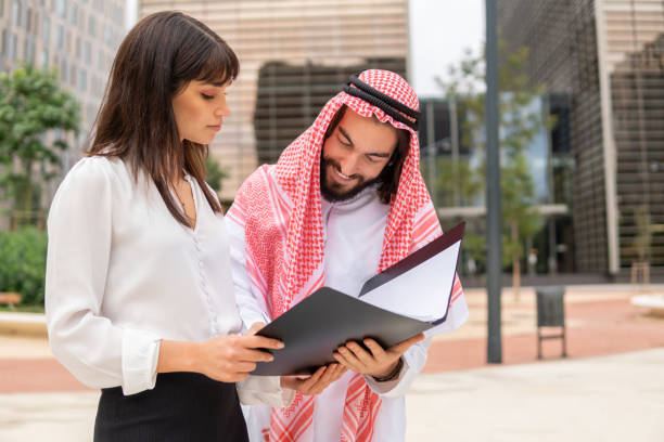istock Happy arab man client signing documents while standing outdoors with young caucasian businesswoman 1352892680