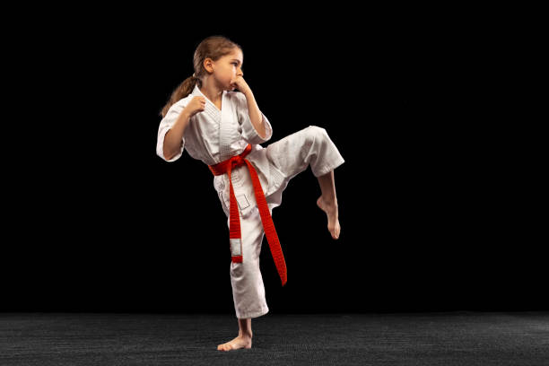 karate, chica de taekwondo con cinturón amarillo aislado sobre fondo oscuro en luz neón. concepto de deporte, educación, habilidades - karate child judo belt fotografías e imágenes de stock