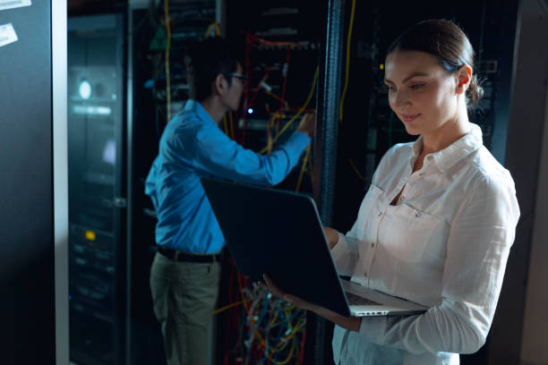 istock Caucasian female engineer using laptop and asian male engineer inspecting in computer server room 1352896059