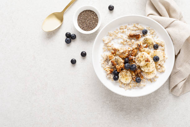 haferflockenschüssel. haferbrei mit banane, heidelbeere, walnuss, chiasamen und mandelmilch für gesundes frühstück oder mittagessen. gesundes essen, ernährung. draufsicht. - oatmeal stock-fotos und bilder