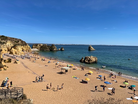 Praia Dona Ana beach with turquoise sea water and cliffs, flying seagulls over the beach, Portugal. Beautiful Dona Ana Beach (Praia Dona Ana) in Lagos, Algarve, Portugal.