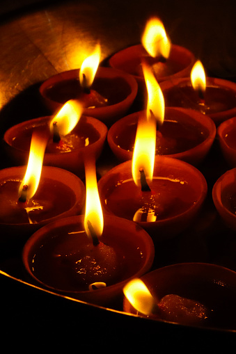 Stock photo showing close-up view of lit clay diyas (oil lamps) on a metal tray (thali) to celebrate the festival of lights - Diwali.