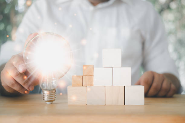 istock Hand holding light bulb that shine glitter and empty stack of wood block. Idea concept with innovation and inspiration. 1352898862