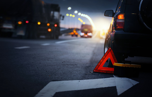 Señal roja de parada de emergencia (señal de advertencia de triángulo rojo) y automóvil SUV negro roto. photo