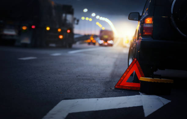 segnale di stop di emergenza rosso (segnale di avvertimento triangolo rosso) e auto suv nera rotta. - ciglio della strada foto e immagini stock