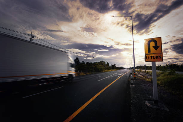 Blurry container truck drive through U-turn sign. stock photo