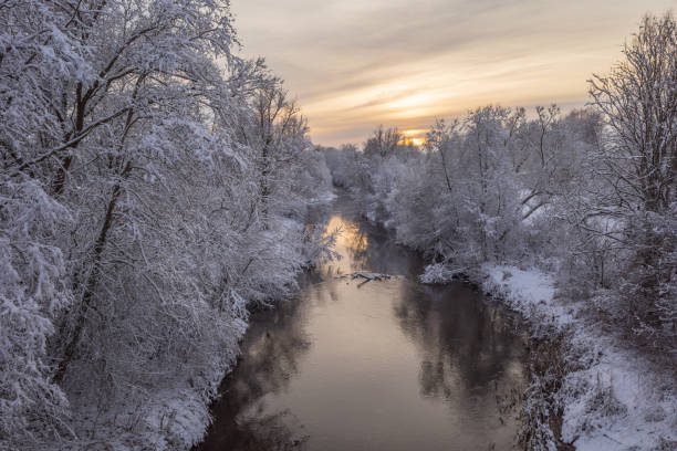 istock Small river running through the white snowy forest in sunset 1352901759
